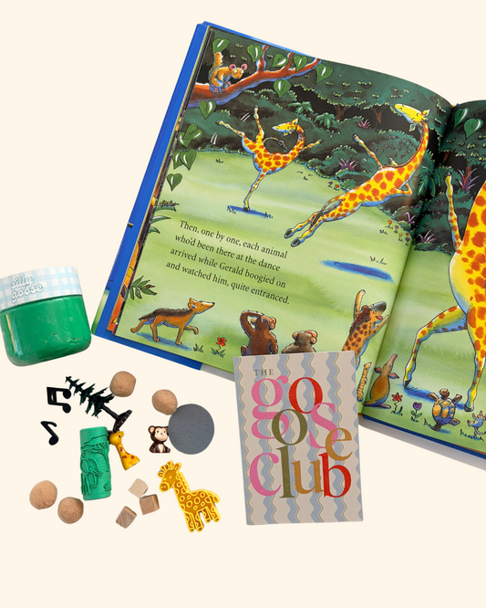 Sensory playdough and giraffe themed accessories beside an open Giraffes Can't Dance book